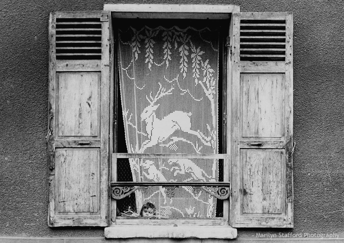 Child at window with lace curtain, Paris, c1950.